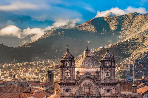 Wide shot of South American city, mountain range in distance, large cathedral in foreground. 