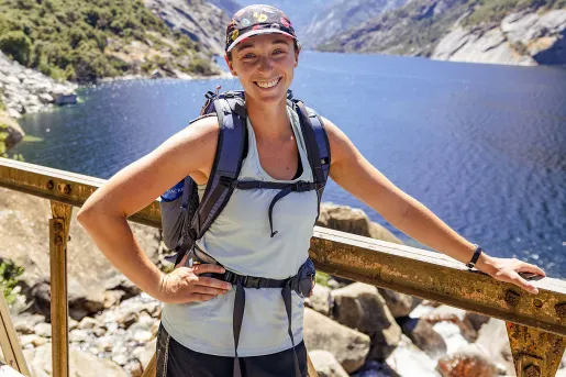 Hiker posing on a cliffside, leaning on a rail.