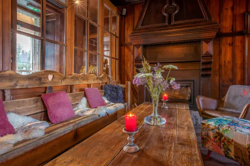 Indoor lodge with wooden furniture and leather seats, with a fireplace at the end of the room