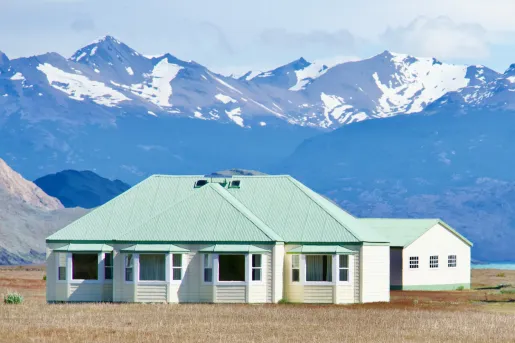 house with green roof in front of snow capped mountains