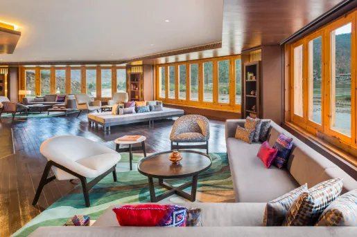 Lounge with gray sofas surrounded by large windows with wooden trim