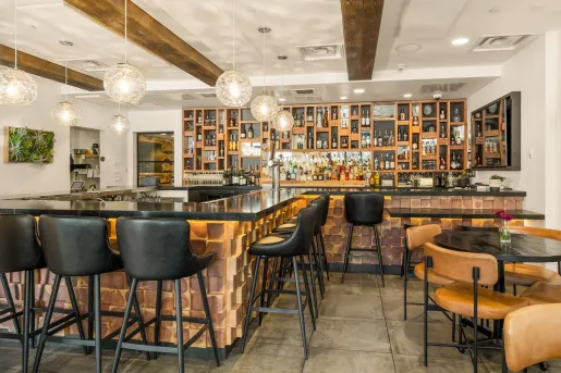 Indoor bar and lounge with black stools and cushioned, leather chairs
