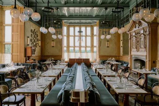 Indoor dining area with green couches in the center and vases on each table