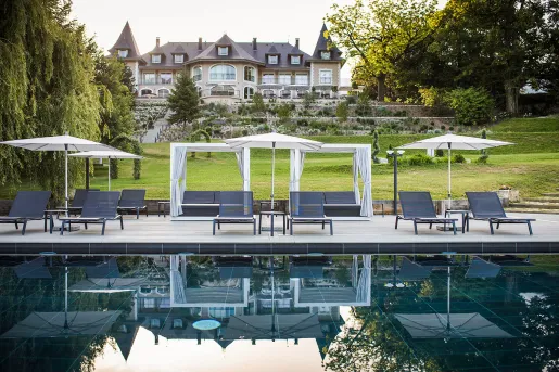 Outdoor pool with umbrellas with a castle-like building in the background