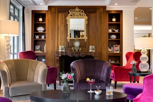 Indoor lounge with purple and gray cushioned chairs in front of a fireplace