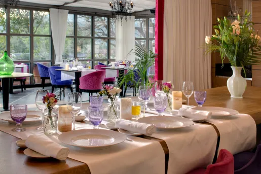 Dining area with pink and blue cushioned chairs and purple glasses on the table