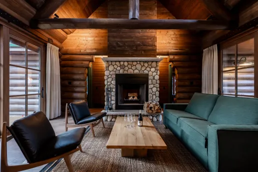 Indoor lodge lobby with black and green sofas surrounding a stone fireplace