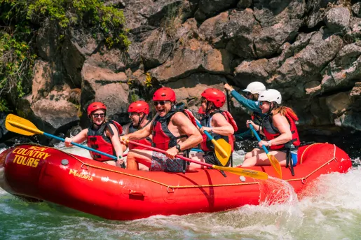 Group of people on a red raft, paddling through a river