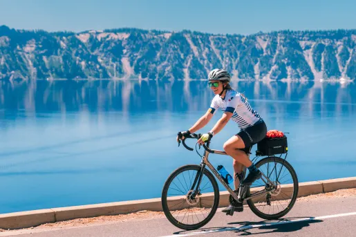 Woman smiling while riding a bike next to a large lake