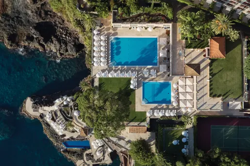 Sky view of outdoor pools with a hotel building next to it