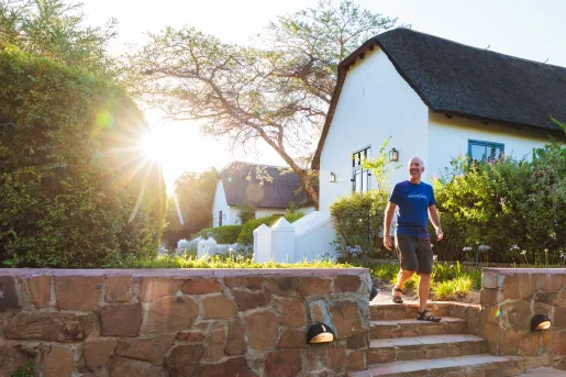 Man walking down a small stairway, with small villas behind him