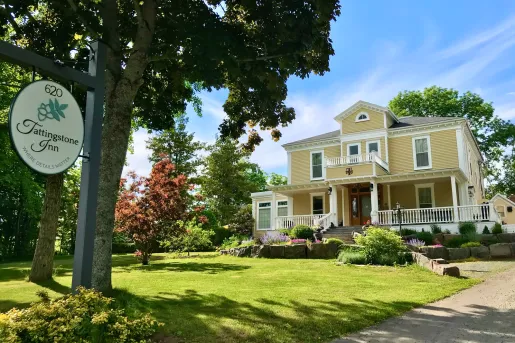Exterior view of yellow building with a grass area in front, surrounded by trees