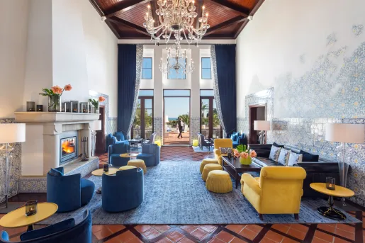 Indoor lounge with a large chandelier, and blue and yellow cushioned seats