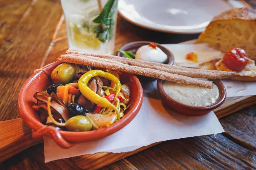 Wooden blank with breadsticks and a small bowl of a mixed vegetable salad
