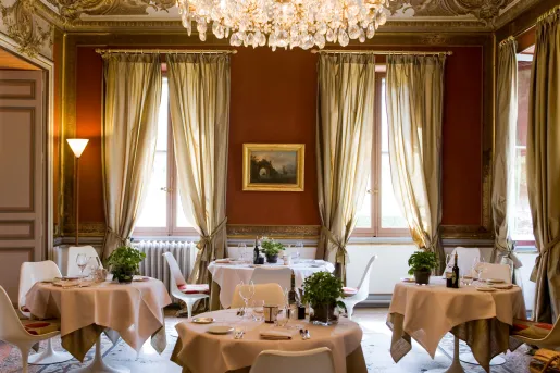 Dining area with 4 circular tables and a chandelier on the ceiling