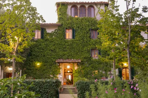 Exterior view of two-story building covered in plants and moss