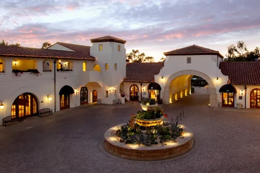 Courtyard with a circular fountain with white and tan buildings surrounding