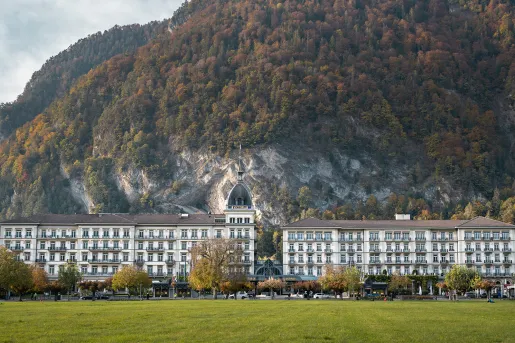 Wide, exterior view of hotel building with large mountains in the background