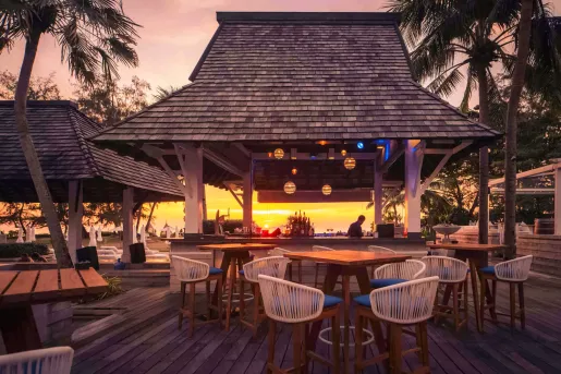 Outdoor huts with woven chairs and wooden tables
