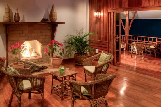 Indoor cabin room with a fireplace and woven chairs, with a patio to the right