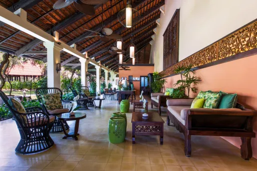 Outdoor patio with cushioned chairs on tile flooring, looking out to a garden