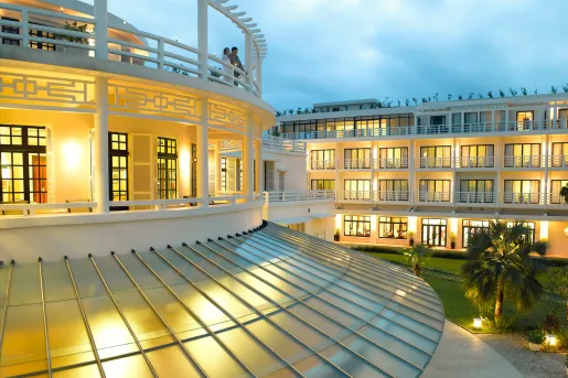 Exterior view of illuminated balconies with two people standing , looking out to other buildings