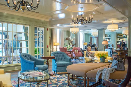 Hotel lobby with large cushioned seats, with people sitting down and reading