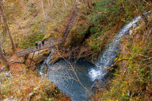 a waterfall falling into a lake, next to a hiking path