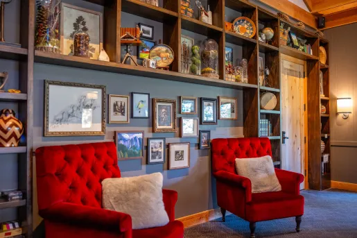 Two red chairs in front of a wall full of paintings and antique trinkets