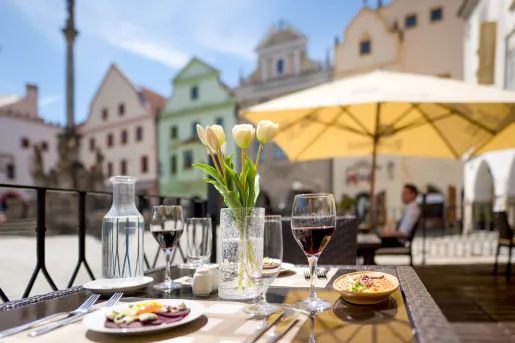 Outdoor dining table with a pot of flowers in the center, and two glasses of wine