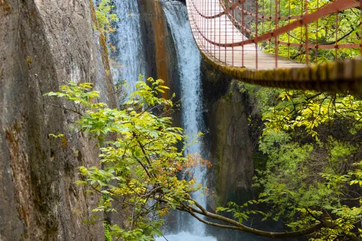 View of a long, wooden bridge over an active waterfall