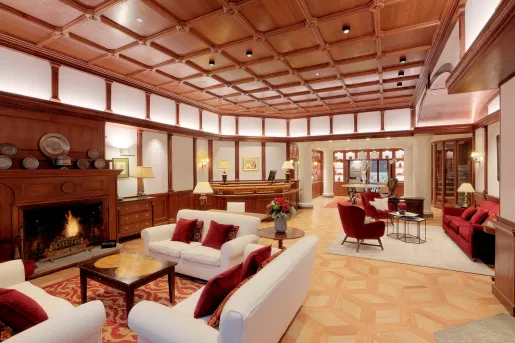 Hotel lobb with wooden ceilings and white walls, with white sofas and red pillows