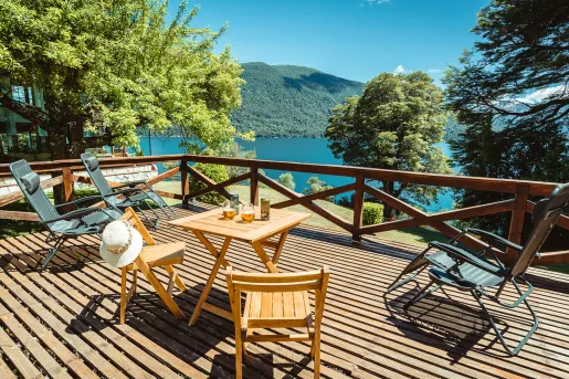 Metal chairs and tables on a patio with a lake in the background