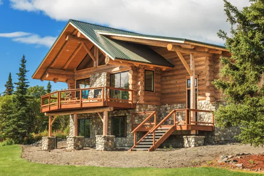 Exterior view of large wooden and stone cabin with trees surrounding