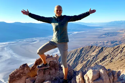 Woman standing on top of a cliff with her arms wide open
