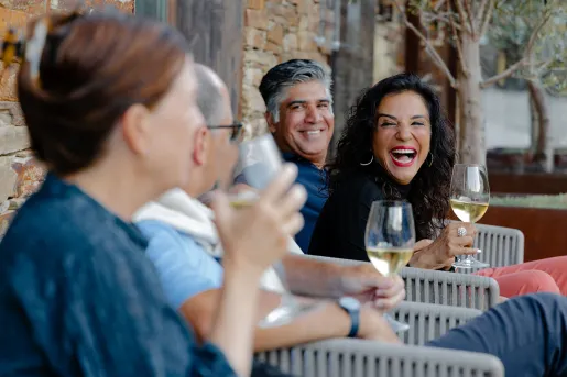 Group of people smiling and laughing while holding wine glasses