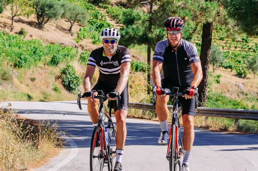 Two men wearing biking gear and riding bikes on a road