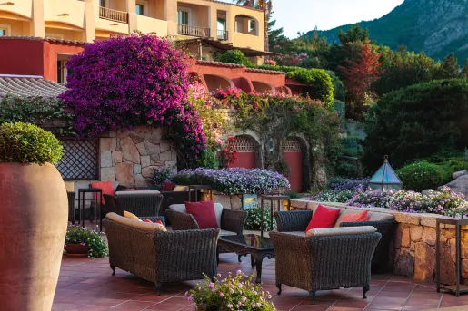 Outdoor patio with woven, cushioned chairs with a garden in the background