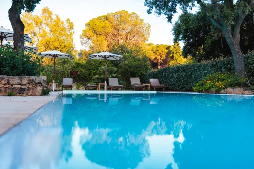 Outdoor pool with gray reclining chairs and umbrellas