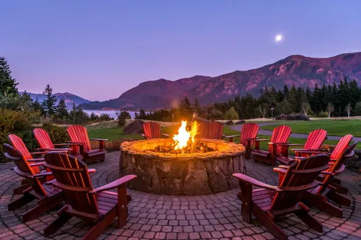 Outdoor stone firepit with red chairs surrounding it
