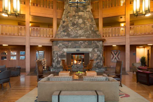 Hotel lobby with large light fixtures and a stone fireplace in the center