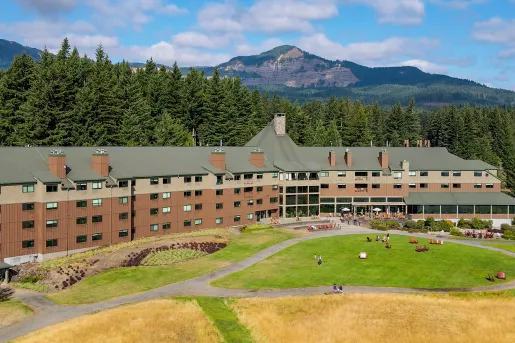 Exterior view of large brown hotel building, with a grass field in front