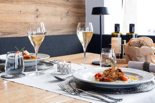 Dining table with two plates of prepared lobster and two wine glasses