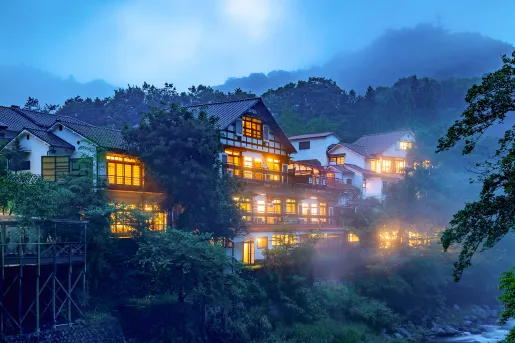 Exterior view of large, white building with illuminated lights and fog outdoors