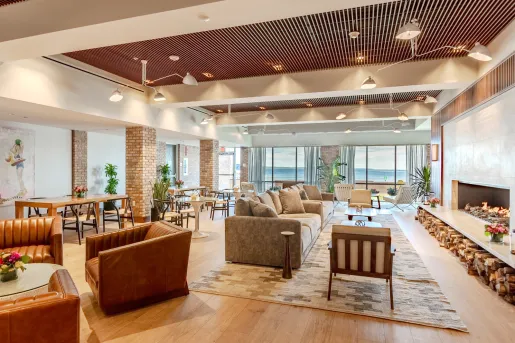 Lounge and seating area in front of a large fireplace and large windows in the back