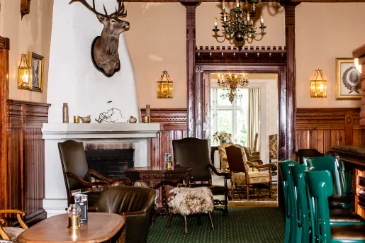 Bar and lounge with cushioned chairs surrounding a fireplace