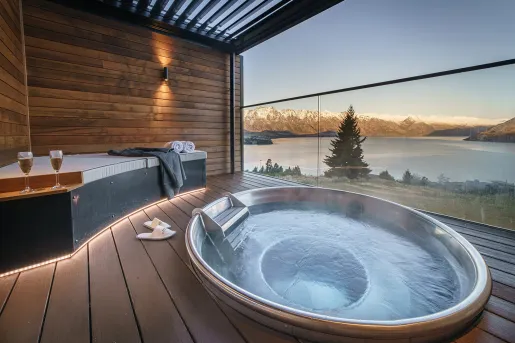Outdoor hot tub overlooking a lake and snow-capped mountains