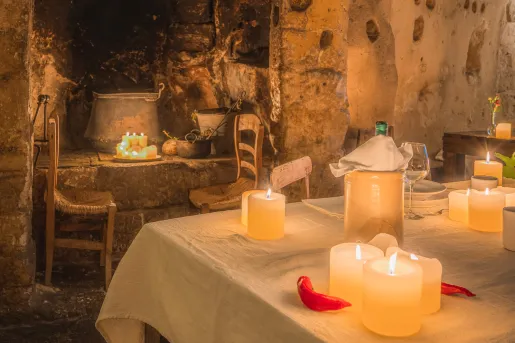 Dining table in a rustic room, with stone walls and candles along the room