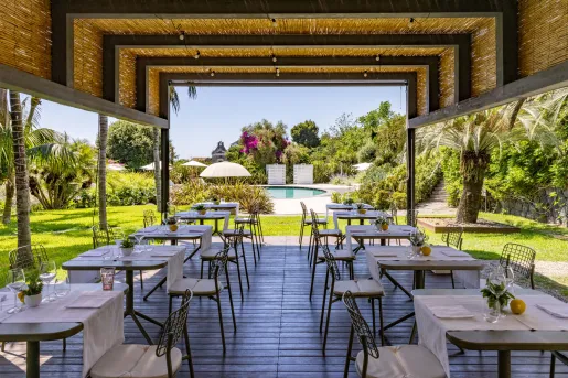 Outdoor patio with rows of dining tables and chairs, with an outdoor pool in the background