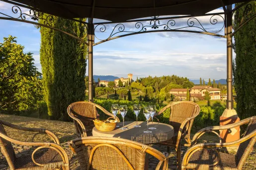 Outdoor patio with woven chairs and tables, looking out to a valley